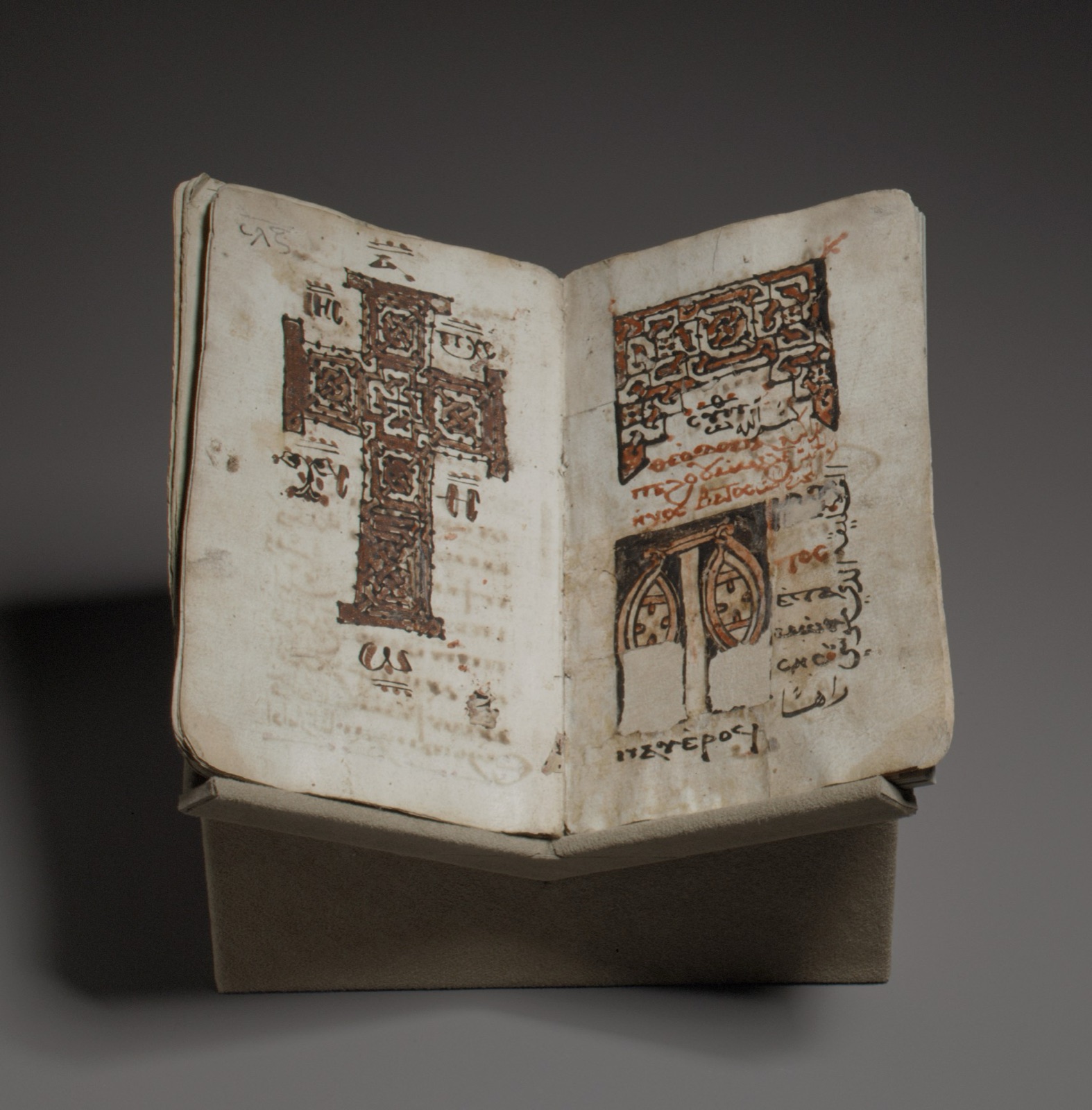 Open illustrated Coptic liturgical codex with text columns and decorated figures